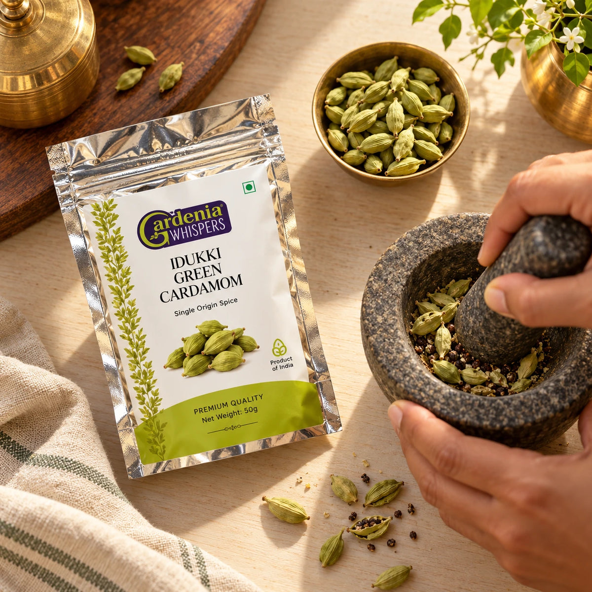 Gardenia Whispers Idukki Green Cardamom 50g single origin pack with whole elaichi pods being crushed in stone mortar pestle